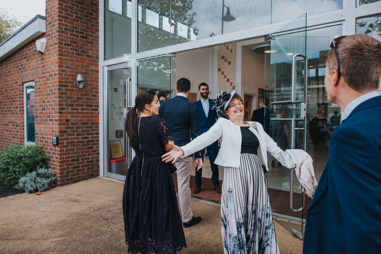 excited mother of bride welcoming guests at church